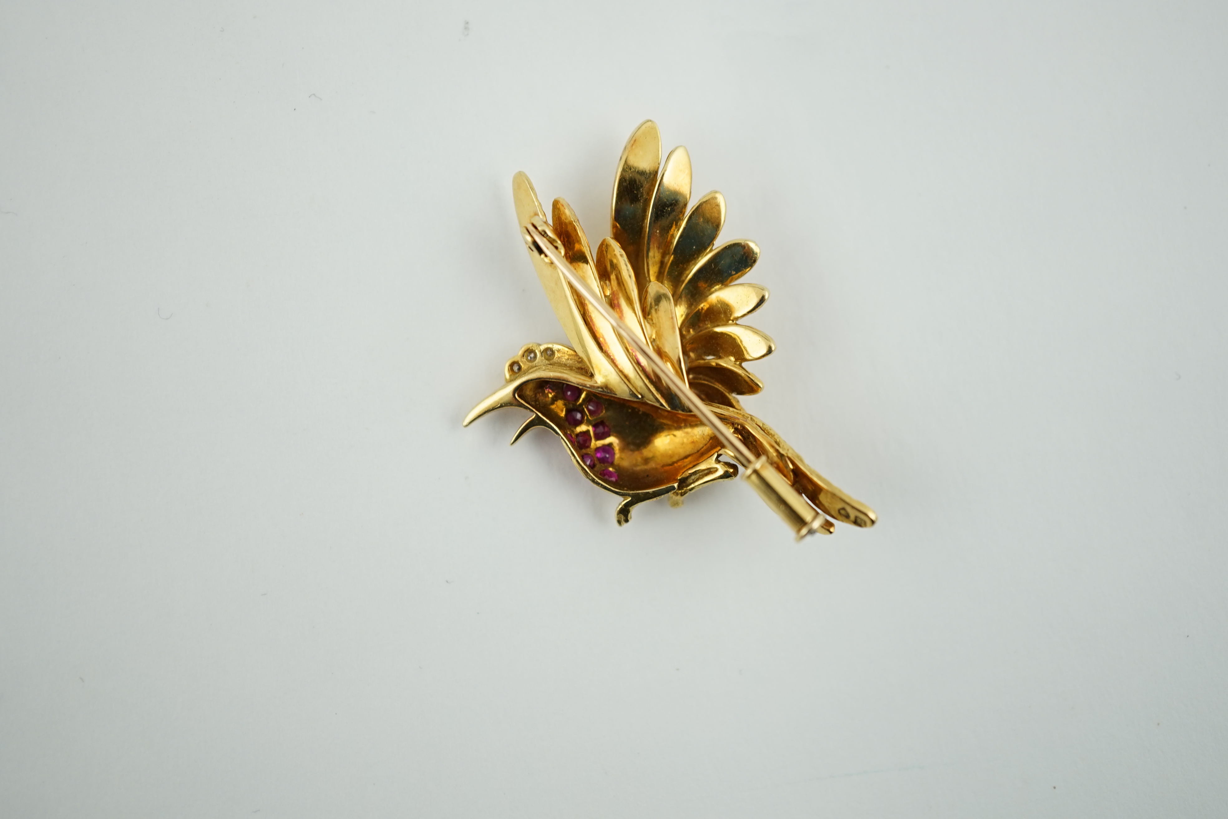 A 20th century French 18ct gold, ruby, emerald and diamond cluster set brooch, modelled as a bird in flight